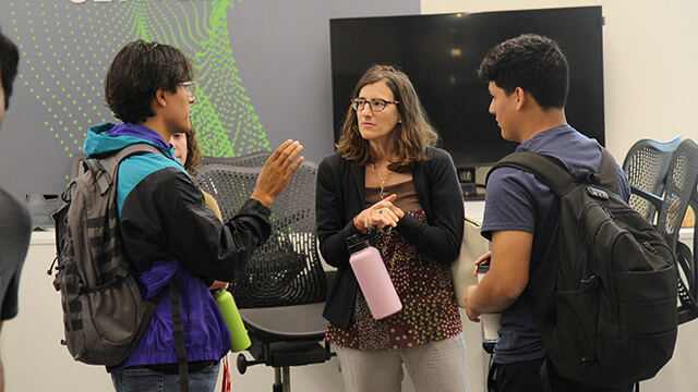A professor and a student listen to another student